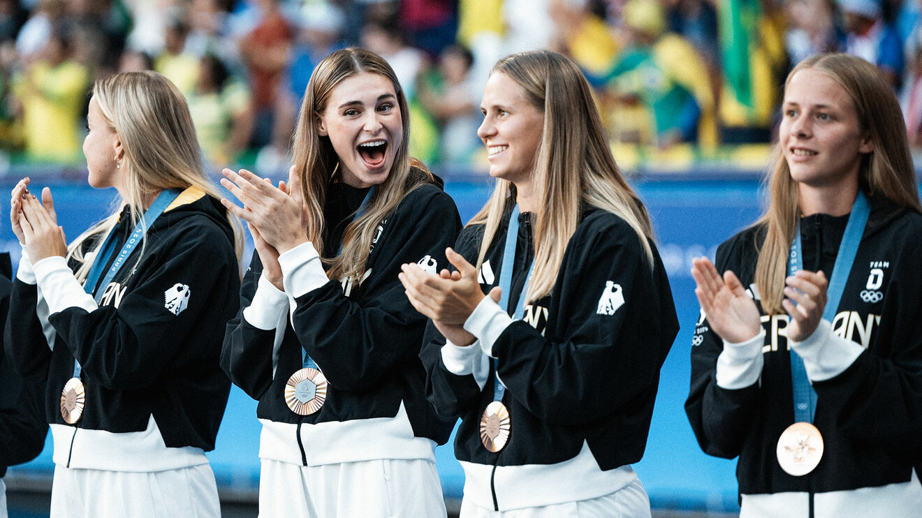 VfL-Wolfsburg-Spielerinnen Jule Brand und Vivien Endemann mit ihren Mitspielerinnen bei der Medaillen-Vergabe der olympischen Spiele.