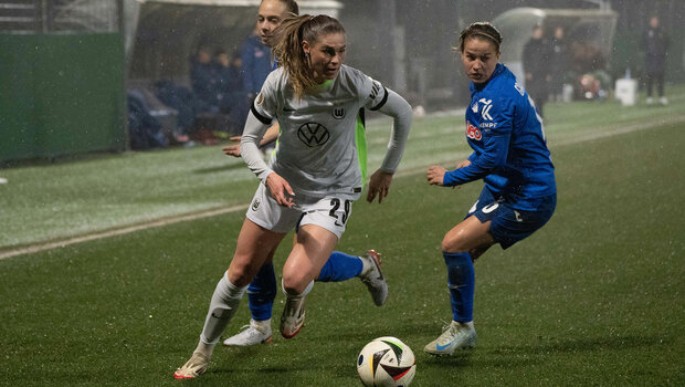 Jule Brand vom VfL-Wolfsburg mit dem linken Fuß am Ball. Sie wird von hinten von zwei Gegenspielerinnen gefolgt. 