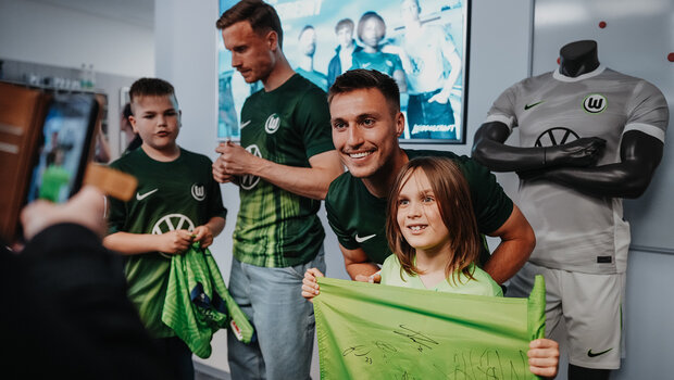 Der VfL-Wolfsburg-Spieler Kilian Fischer macht ein Foto mit einem Mädchen.