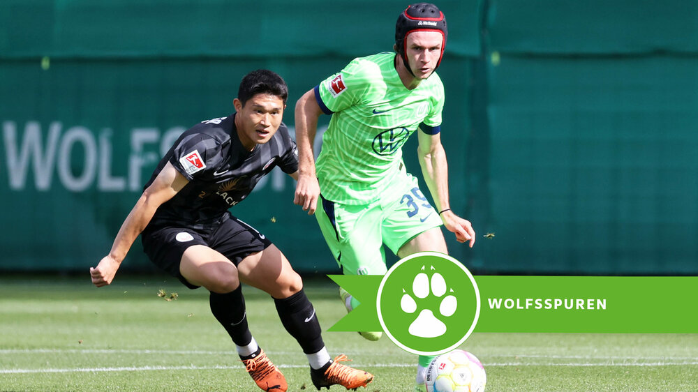 VfL Wolfsburg Spieler Wimmer mit Kopfschutz im Zweikampf um den Ball.