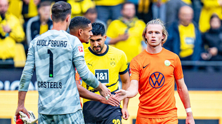 VfL Wolfsburg Spieler Casteels, Lacroix und Wimmer klatschen sich auf dem Feld mit den Händen ab.