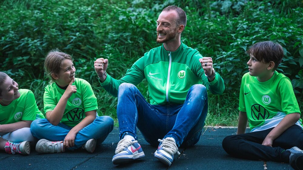 VfL-Wolfsburg-Spieler Maximilian Arnold lacht mit Kindern bei einer der Fragerunde.