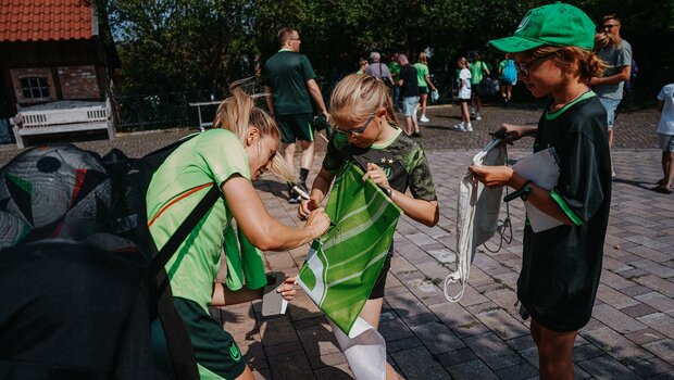 Die VfL-Wolfsburg-Spielerin Rebecka Blomqvist mit einem Stift in der Hand und einem Ballsack auf dem Rücken.