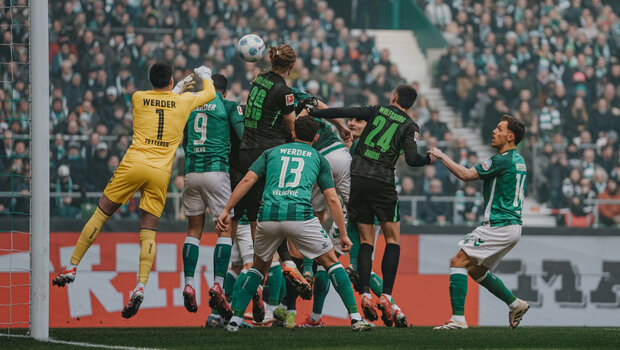 Patrick Wimmer und weitere Spieler des VfL Wolfsburg und Bremen springen für einen Kopfball in die Höhe.