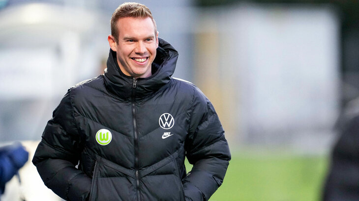 Wölfinnen-Trainer Tommy Stroot lächelt mit den Händen in den Jackentaschen in die Kamera.
