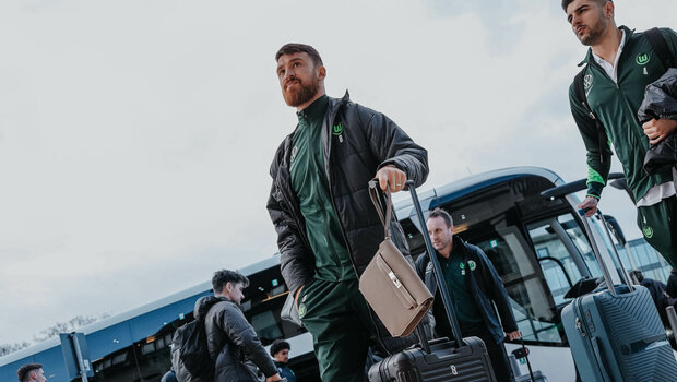 Der VfL-Wolfsburg-Spieler Salih Özcan läuft mit seinem Koffer vor einem Bus.