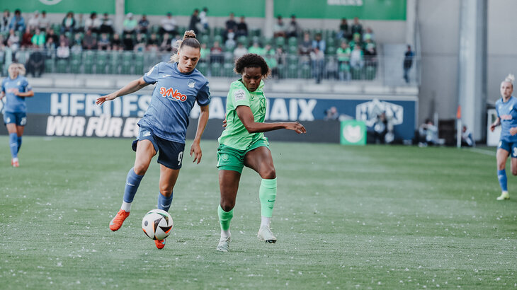 Lineth Beerensteyn vom VfL Wolfsburg Kopf an Kopf mit einer Gegenspielerin. Vor ihnen rollt der Ball.