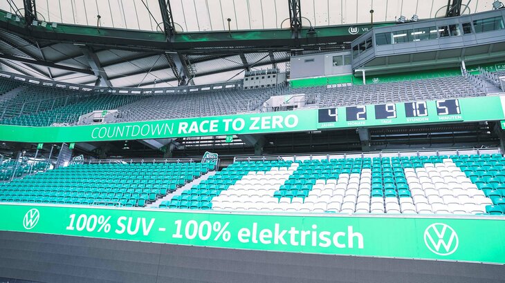 Nahaufnahme des "Race to Zero"-Zählers in einer Bande der Volkswagen Arena vom VfL Wolfsburg.
