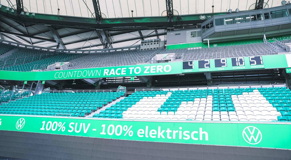 Nahaufnahme des "Race to Zero"-Zählers in einer Bande der Volkswagen Arena vom VfL Wolfsburg.