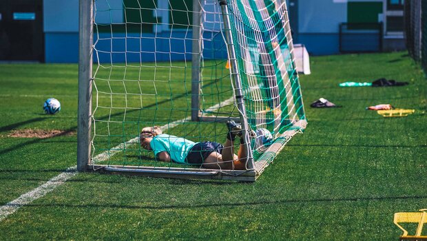 VfL-Wolfsburg-Spielerin Svenja Huth liegt beim Training lachend im Tor.