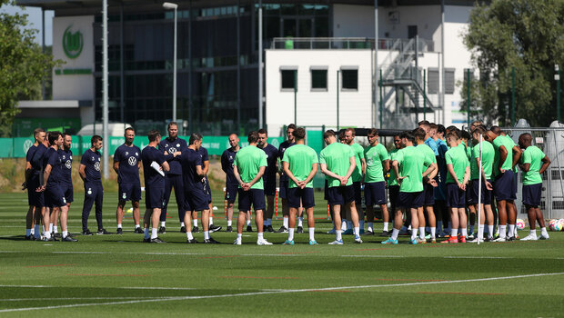 Die Spieler vom VfL Wolfsburg stehen zusammen mit dem Trainerteam auf dem Trainingsplatz.