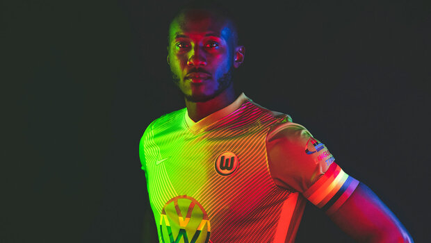 VfL-Wolfsburg-Spieler Josuha Guilavogui posiert in Regenbogenfarben mit einem VfL-Trikot.