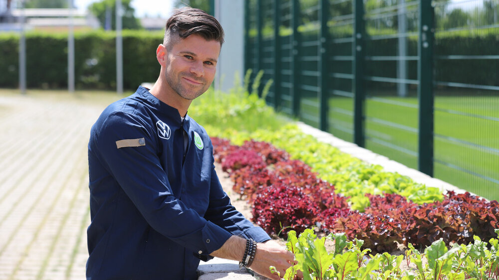 Der Koch des VfL Wolfsburg erntet Gemüse und Kräuter neben dem Trainingsplatz.