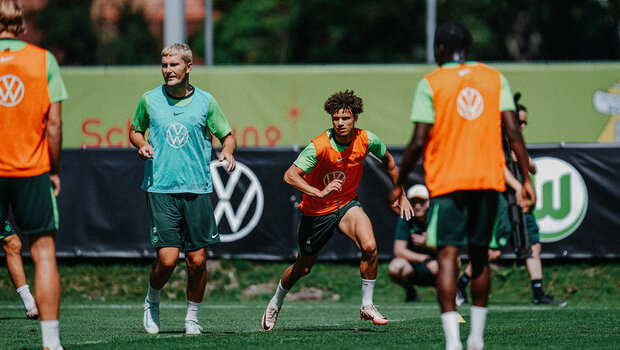 Die beiden VfL-Wolfsburg-Spieler Jonas Wind und Kevin Paredes fokussieren den Ball.
