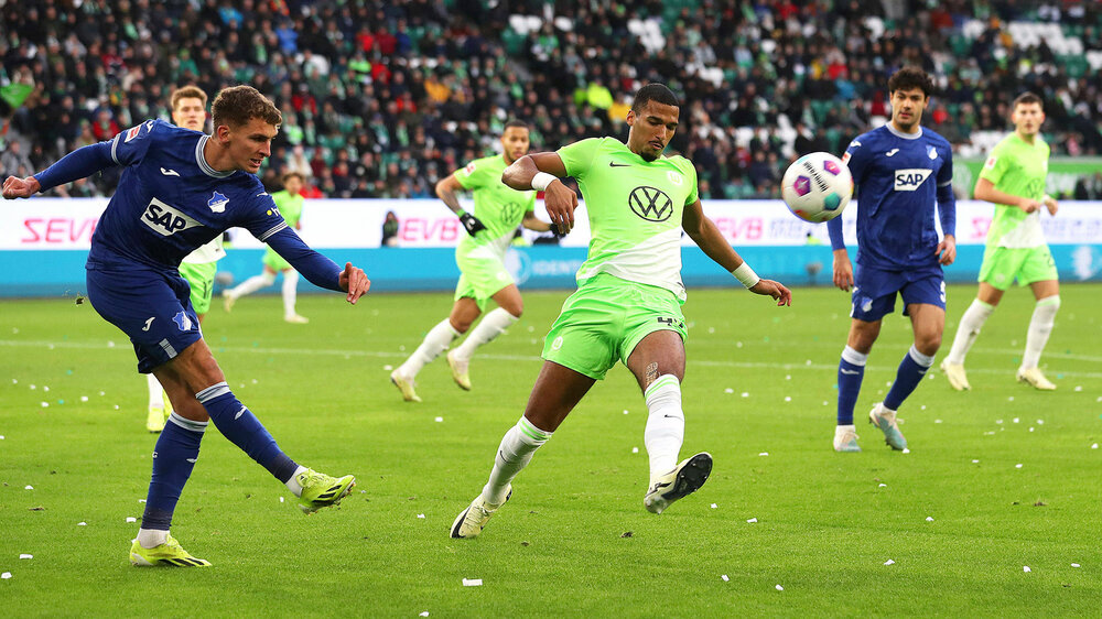 VfL-Wolfsburg-Spieler Jenz versucht einen Schuss von einem Gegenspieler der TSG Hoffenheim zu blocken.