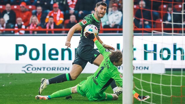 VfL-Wolfsburg-Spieler Jonas Wind schießt den Ball auf Tor und der Unioner Torwart pariert.