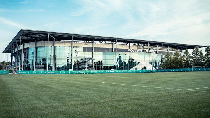 Im Vordergrund ist der Trainingsplatz des VfL Wolfsburg und im Hintergrund die Volkswagen Arena zu sehen.