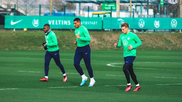 VfL Wolfsburg Spieler Cozza, Lacroix und Mbabu laufen sich vor dem Training warm.