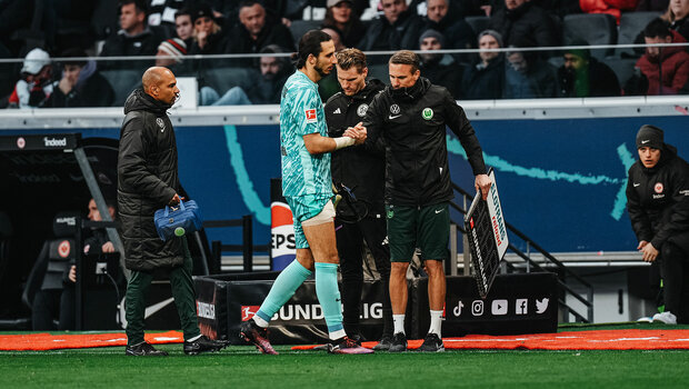 VfL-Wolfsburg-Spieler Kamil Grabara schlägt an der Seitenlinie mit seinem Trainer ein.