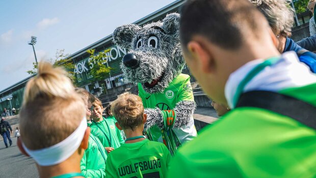 Das VfL-Wolfsburg-Maskottchen Wölfi interagiert mit den Kindern vor dem AOK-Stadion.