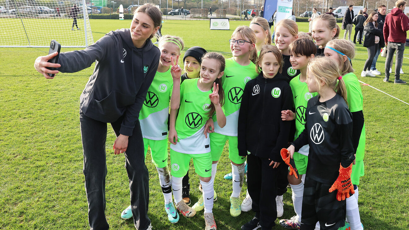 Kinder posieren für ein Foto mit Jule Brand im Training des VfL Wolfsburg.