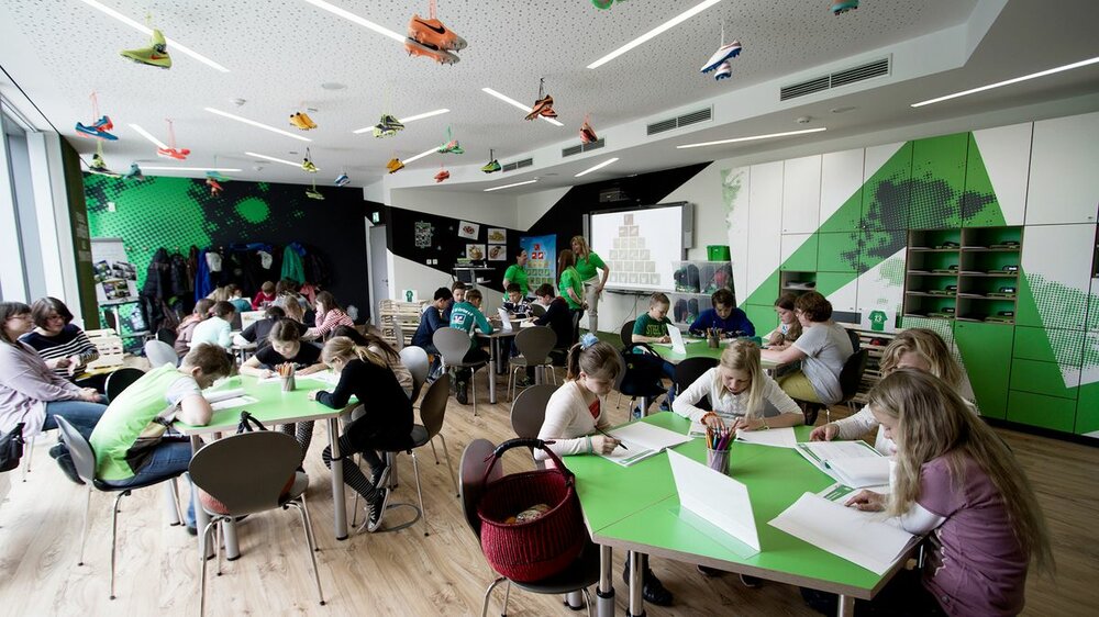 Kinder sitzen im Grün-Weißen Klassenzimmer vom VfL Wolfsburg.