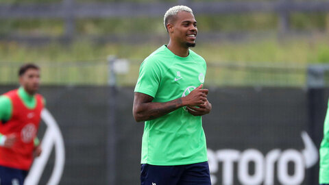Der VfL Wolfsburg-Spieler Lukas Nmecha läuft lachend auf dem Trainingsplatz.