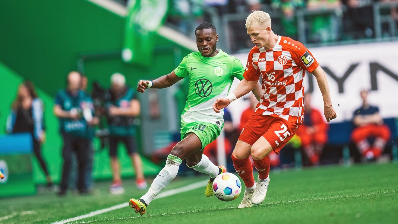 VfL-Wolfsburg-Spieler Ridle Baku läuft hinter einem Mainzer Spieler.