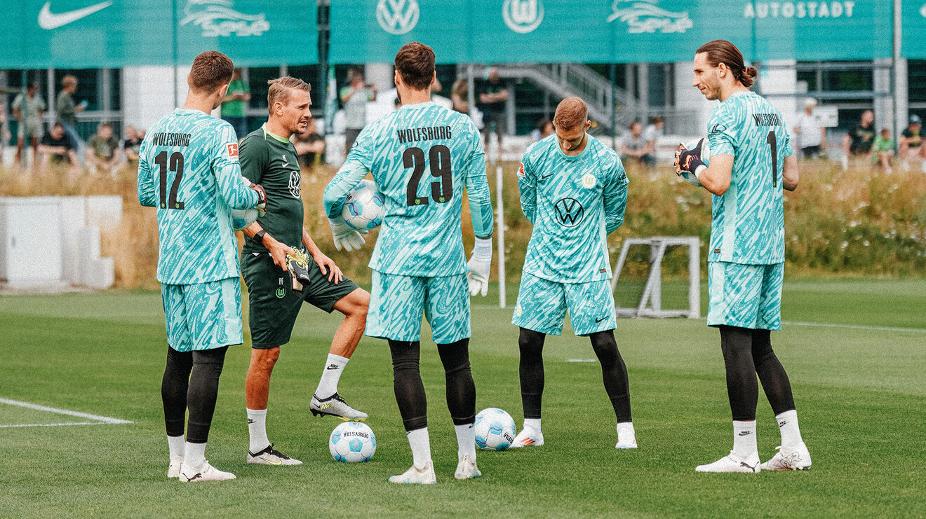 VfL Wolfsburg Towarttrainer Pascal Forsmann spricht mit den Torwarten des VfL, welche im Kreis um ihn herum auf dem Trainingsplatz stehen.