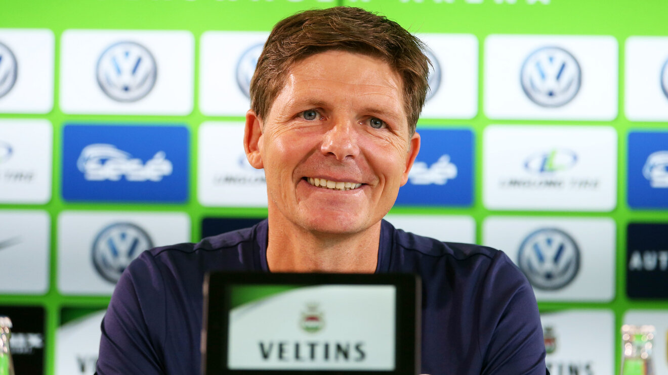Trainer des VfL Wolfsburg Oliver Glasner grinst auf der Pressekonferenz.