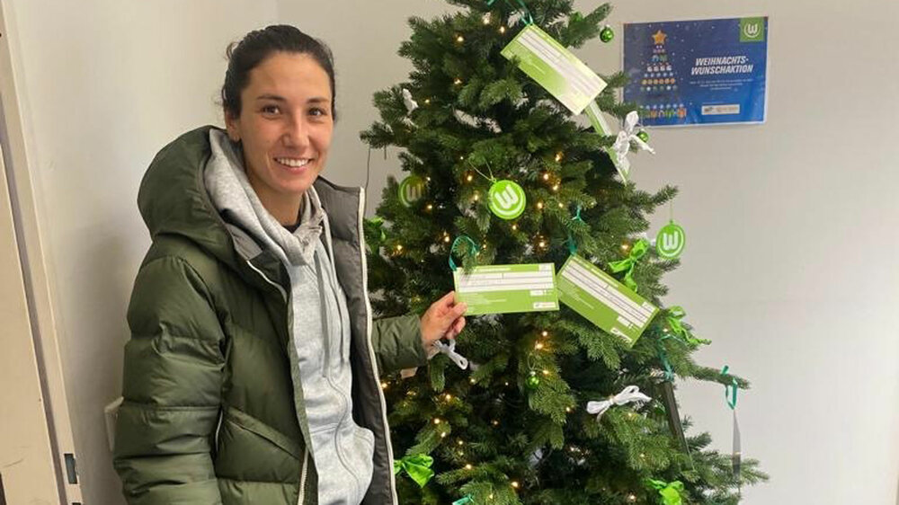 VfL Wolfsburg Spielerin Sara Doorsoun steht vor einem Weihnachtsbaum.