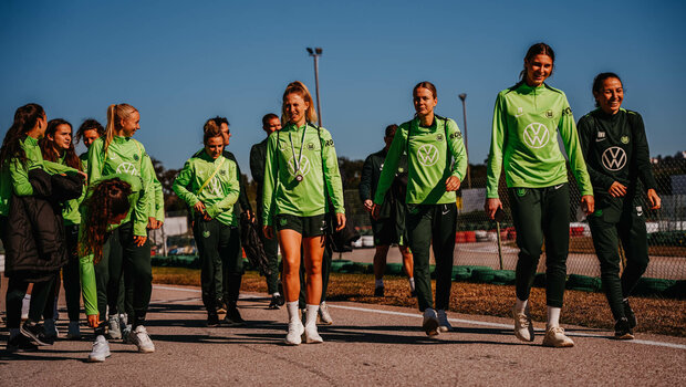 Die VfL-Wolfsburg-Spielerinnen laufen neben einer Kartbahn.