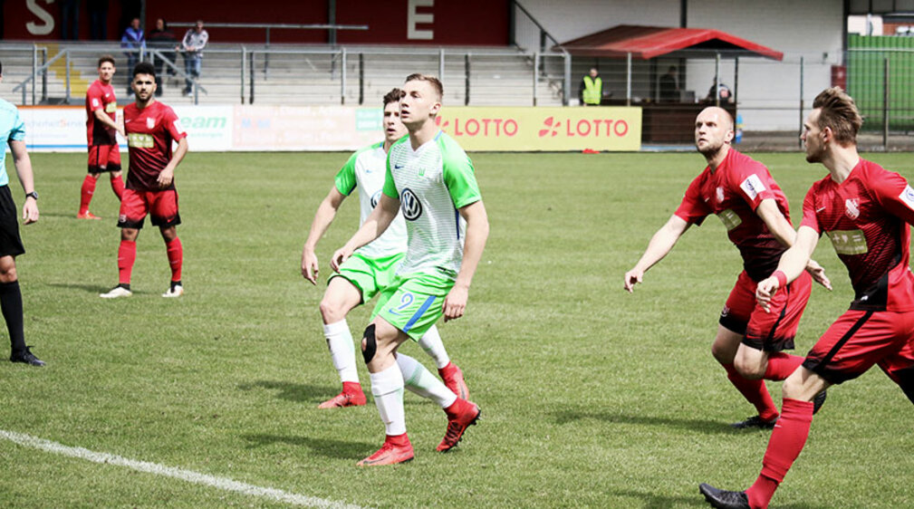 Die Spieler des VfL Wolfsburg und von Havelse blicken einem heranfliegenden Ball entgegen.