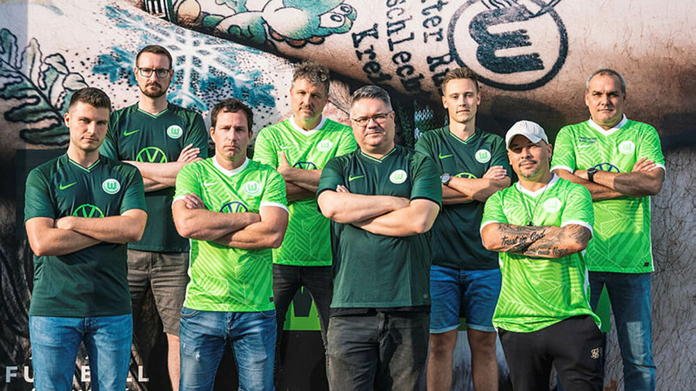 Die Macher des VfL Wolfsburg Wölferadios posieren vor dem Fanshop an der Volkswagen Arena.