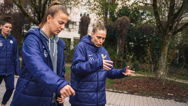 Kim Kulig vom VfL Wolfsburg spricht mit Spielerin Lynn Wilms und gestikuliert dabei.