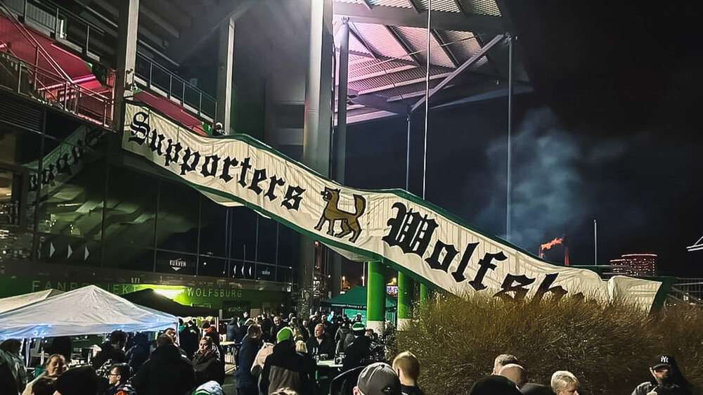 Fans des VfL Wolfsburg feiern vor der Volkswagen Arena das Tonnenfeuer.