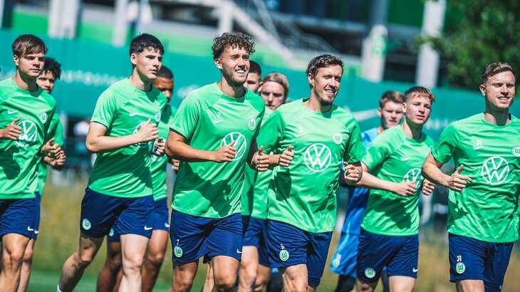 VfL Wolfsburg Spieler laufen sich vor dem Training war, vorneweg laufen und lachen Waldschmidt und Kruse.