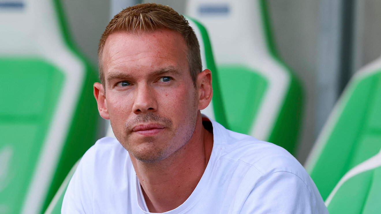 Der VfL-Wolfsburg-Trainer Tommy Stroot sitzt auf der Bank.
