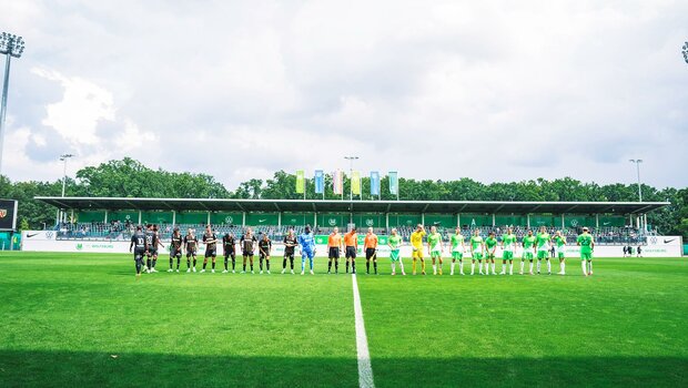 Die Spieler des VfL Wolfsburg und RC Lens stehen am Mittelkreis.