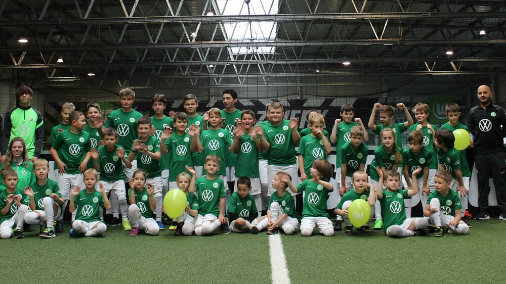 Ein Gruppenbild mit Trainern der Fußballschule des VfL Wolfsburg sowie urkainischen Kindern.