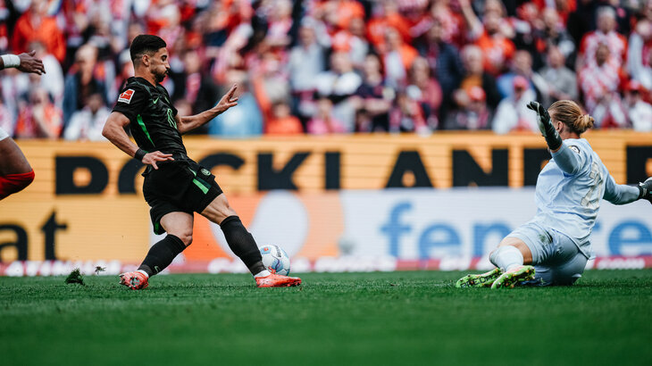 Der VfL-Wolfsburg-Spieler Mohammed Amoura läuft mit dem Ball um den Torhüter.