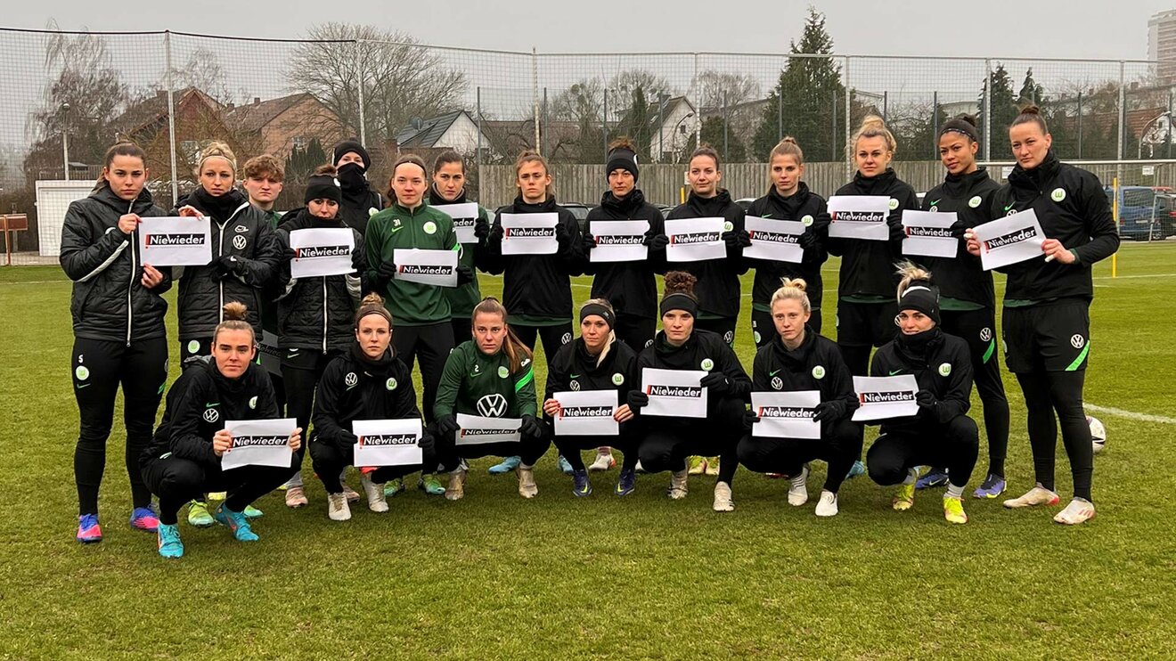 Die Frauen des VfL Wolfsburg halten ein Schild für die Aktion Nie Wieder in ihren Händen.
