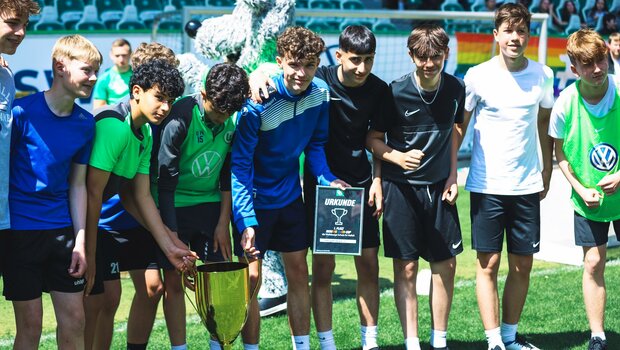 Die Sieger des Vielfalts-Cup vom VfL Wolfsburg posieren für ein Gruppenfoto mit dem Pokal und der Urkunde.