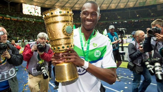 VfL-Wolfsburg-Spieler Josuha Guilavogui präsentiert stolz den gewonnenen DFB-Pokal.