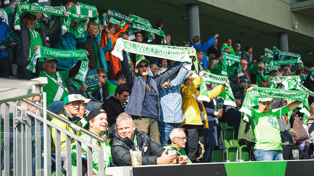 Fans der Frauen des VfL Wolfsburg halten Schals hoch.