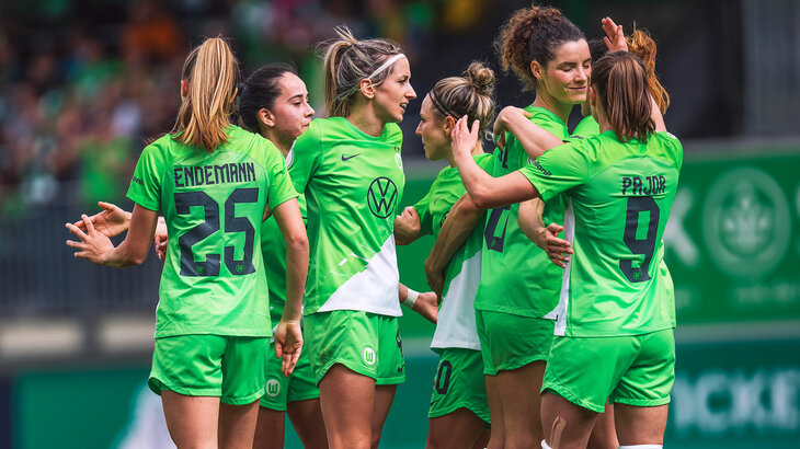 Die Spielerinnen des VfL Wolfsburg stehen jubelnd beisammen.