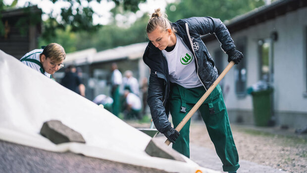 Die VfL Wolfsburg-Spielerin Alex Popp mit einer Schaufel in den Händen beim Wir für Euch-Tag.