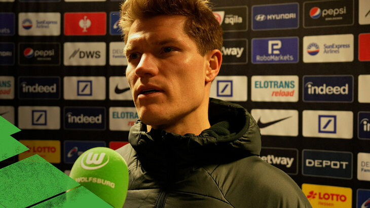 VfL-Wolfsburg-Spieler Kevin Behrens spricht in ein Mikrofon.