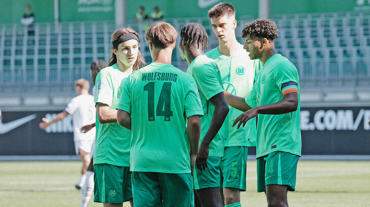 U19-Spieler des VfL Wolfsburg stehen zusammen auf dem Spielfeld.