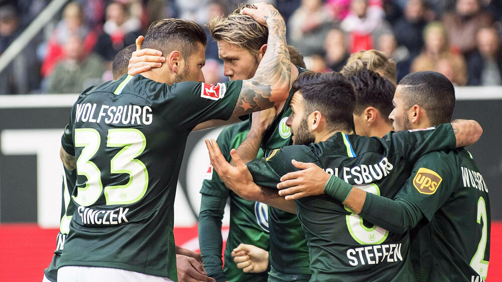 VfL Wolfsburg Spieler um Ginczek und Weghorst jubeln nach einem Treffer auf dem Spielfeld.